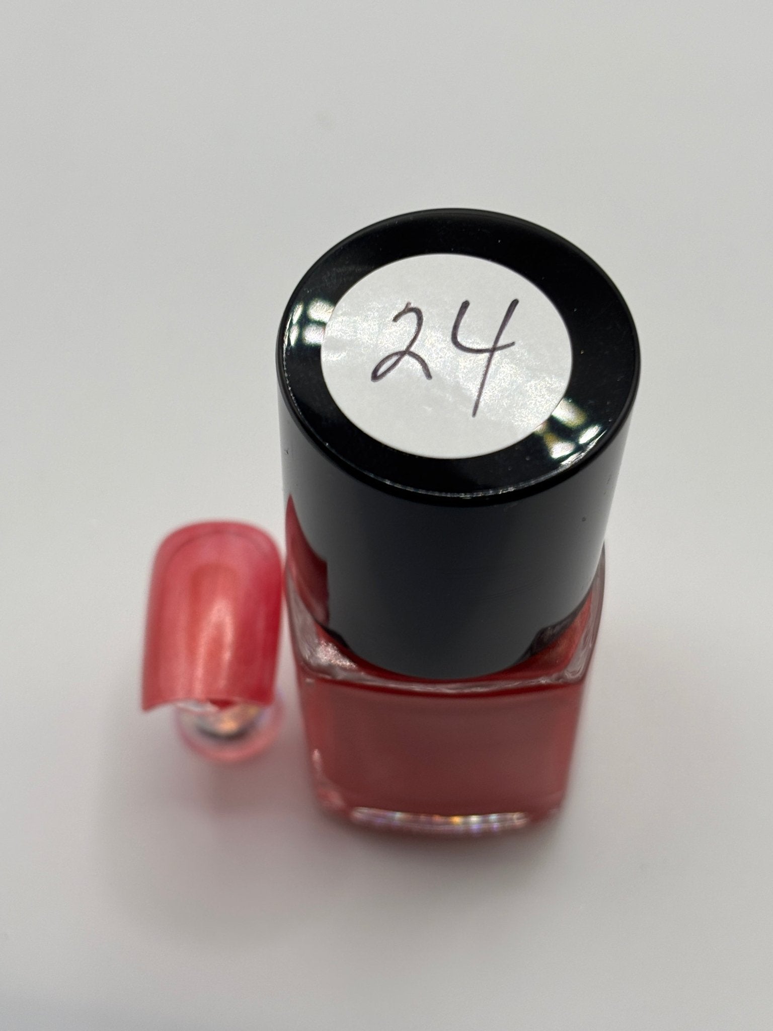 bottle of Berniece and fake nail beside it with #24 on top of bottle