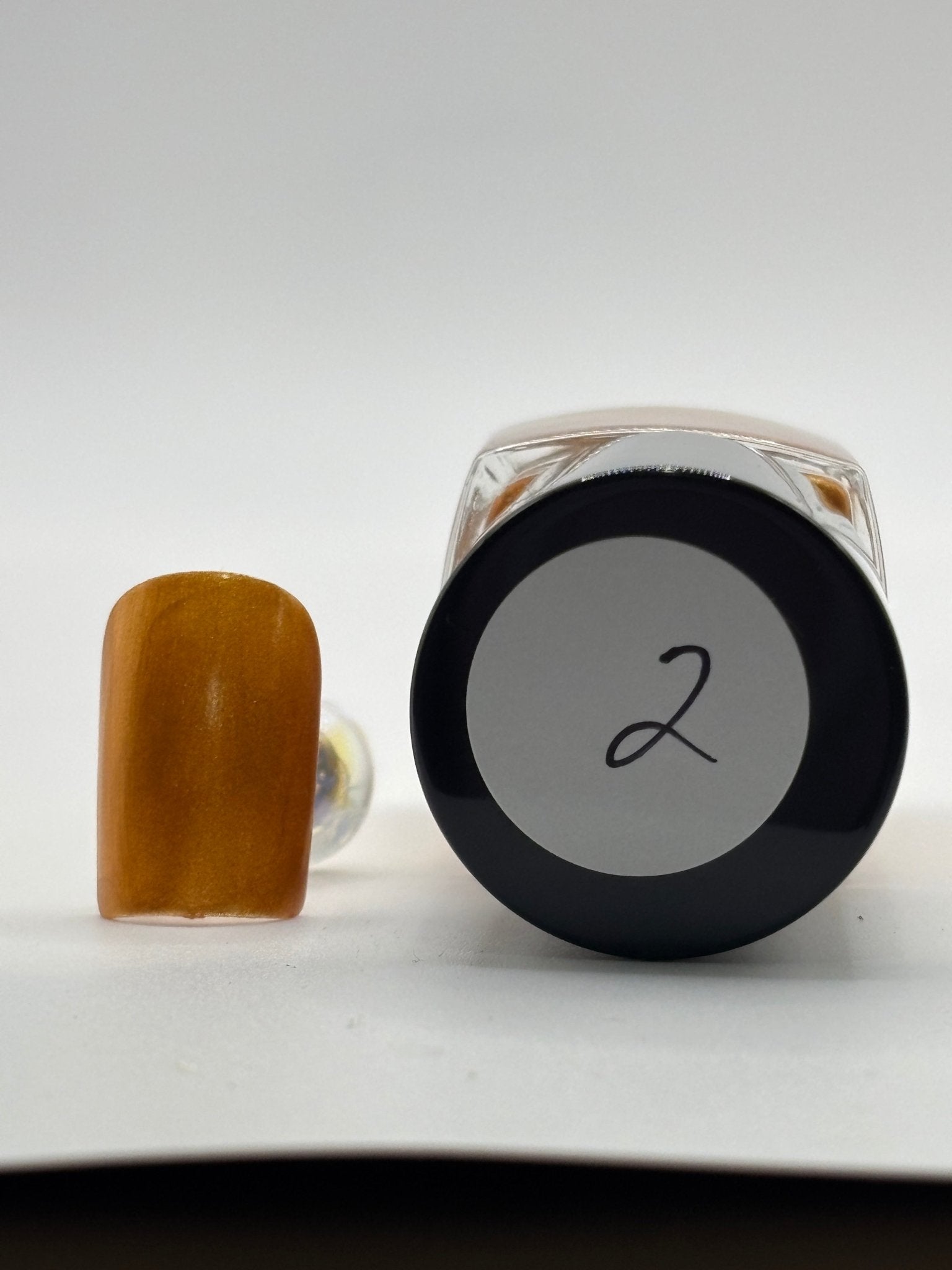 BOTTLE OF ESTHER WITH A FAKE NAIL WITH THE COLOR OF ESTHER SHOWING #2 ON TOP OF BOTTLE