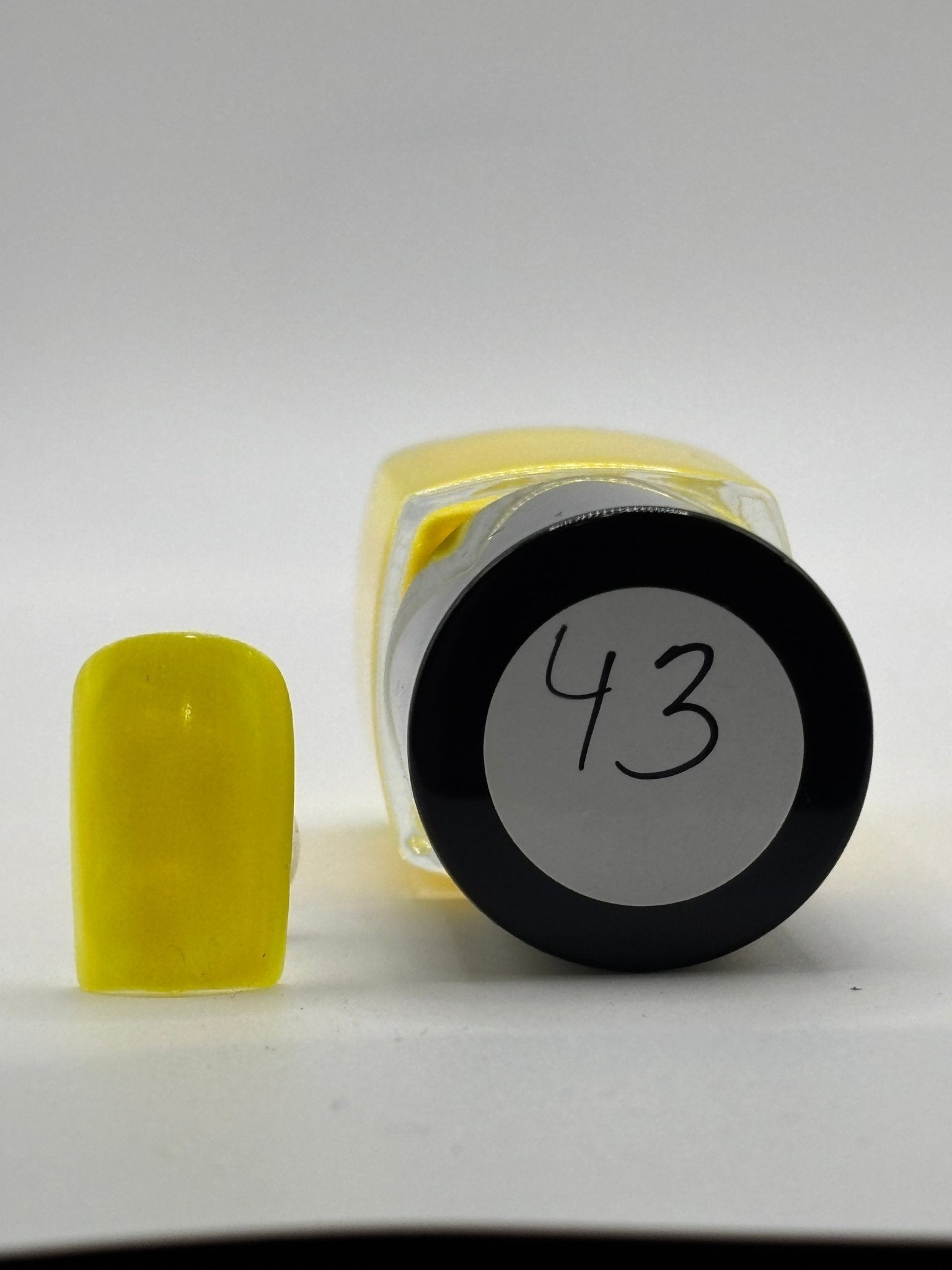 BOTTLE OF GERI NAIL POLISH WITH FAKE NAIL BESIDE IT WITH THE COLOR ON IT SHOWING THE TOP OF THE BOTTLE WITH #43 ON IT