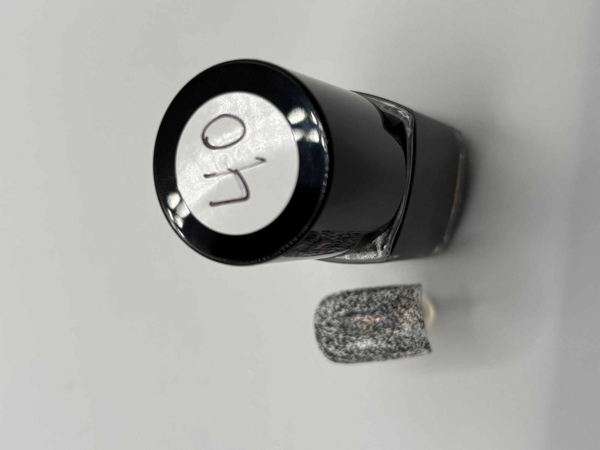 A BOTTLE OF MOLLY BLACK GLITTER POLISH WITH A FAKE FINGERNAIL WITH MOLLY ON IT AND THE TOP OF THE BOTTLE WITH #40 ON IT