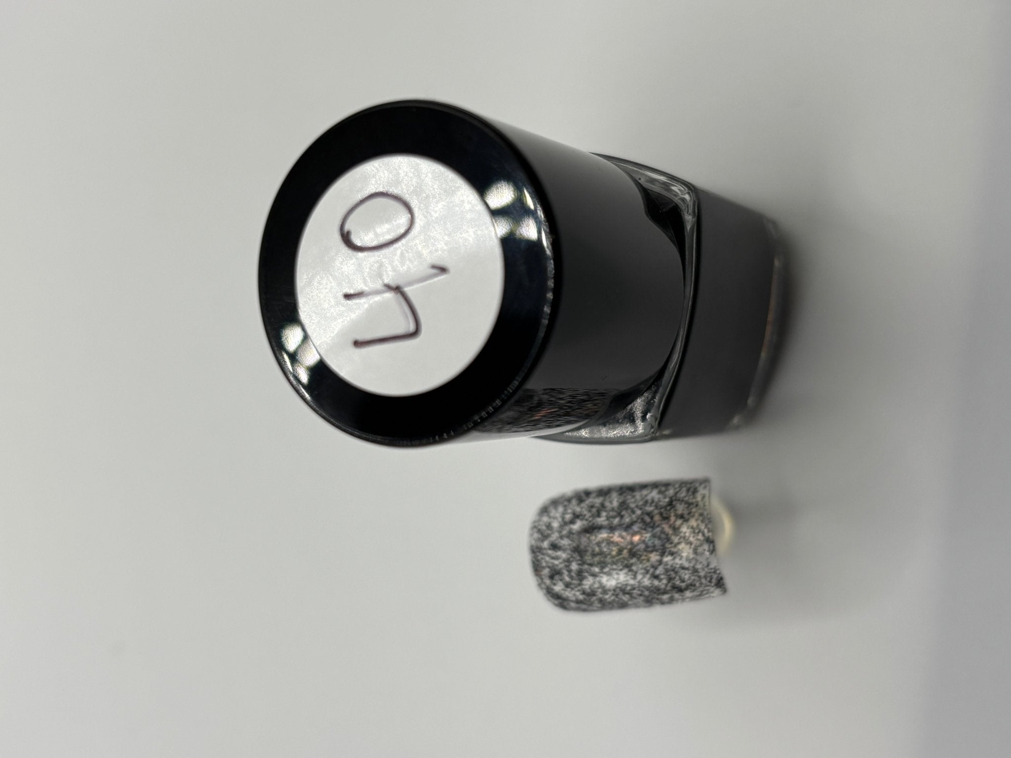 A BOTTLE OF MOLLY BLACK GLITTER POLISH WITH A FAKE FINGERNAIL WITH MOLLY ON IT AND THE TOP OF THE BOTTLE WITH #40 ON IT