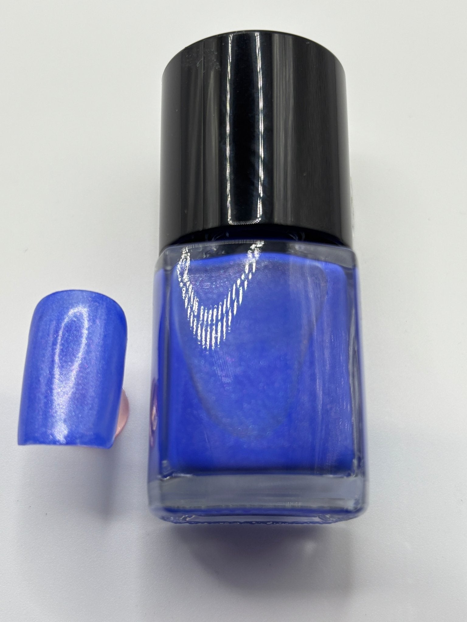 BOTTLE OF TIGE WITH A FAKE FINGERNAIL BESIDE IT THE SAME COLOR