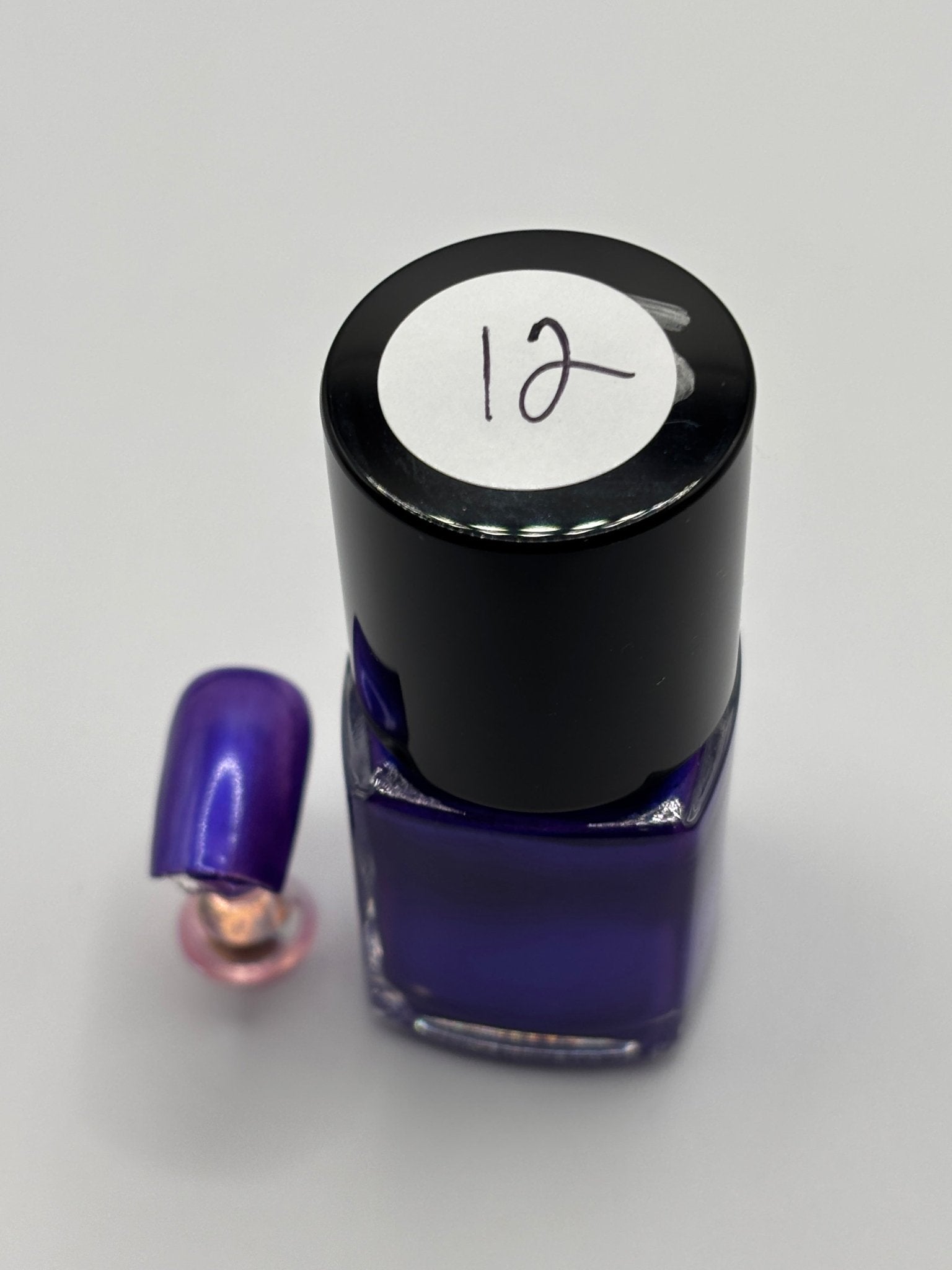 BOTTLE OF VALENCIA WITH NAIL BESIDE IT THE SAME COLOR WITH THE NUMBER 12 ON IT