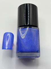 BOTTLE OF TIGE WITH A FAKE FINGERNAIL BESIDE IT THE SAME COLOR